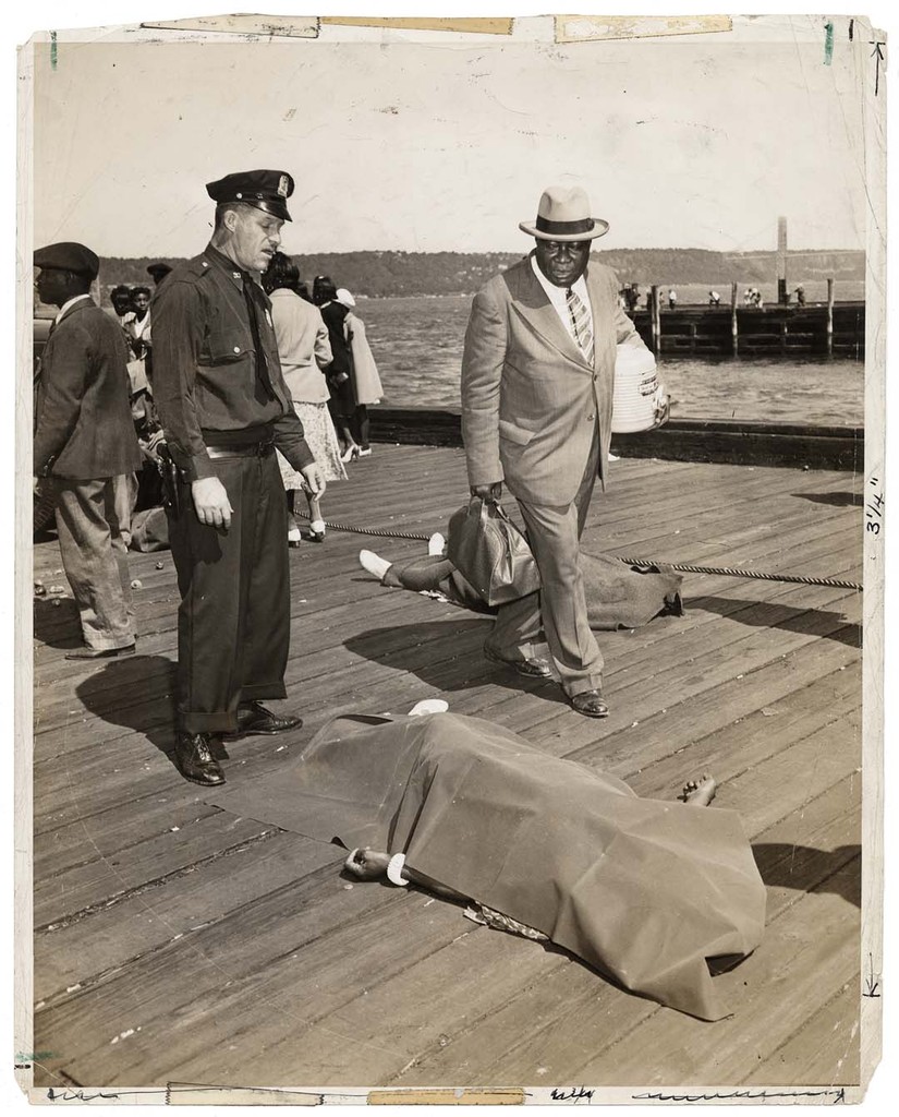 Police officer and lodge member looking at blanket-covered body of woman trampled to death in excursion-ship stampede, New York, August 18, 1941 © Weegee